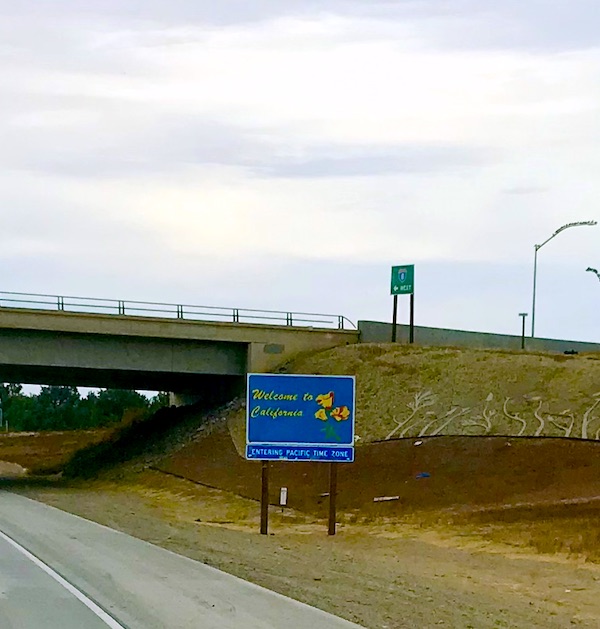 A blue sign on the highway welcoming us to California.