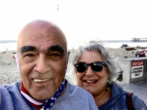 A man and a woman with beach and ocean in the background from California Here We Come