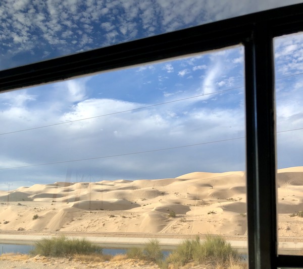 California Here We Come as we pass desert sand dunes seem through an RV window.