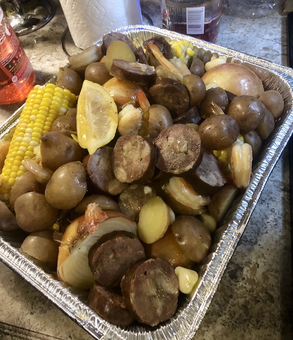 A foil pan filled with seafood, potatoes and corn on the cob en route Coast to Coast We Did It!