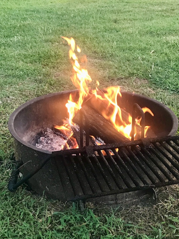 A fire pit on a lawn with a blazing fire enjoyed en route Coast to Coast We Did It!