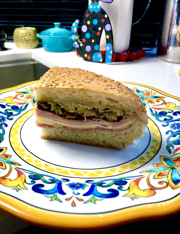 A colorful plate topped with a wedge of an Italian sandwich eaten en route Coast to Coast We Did It!