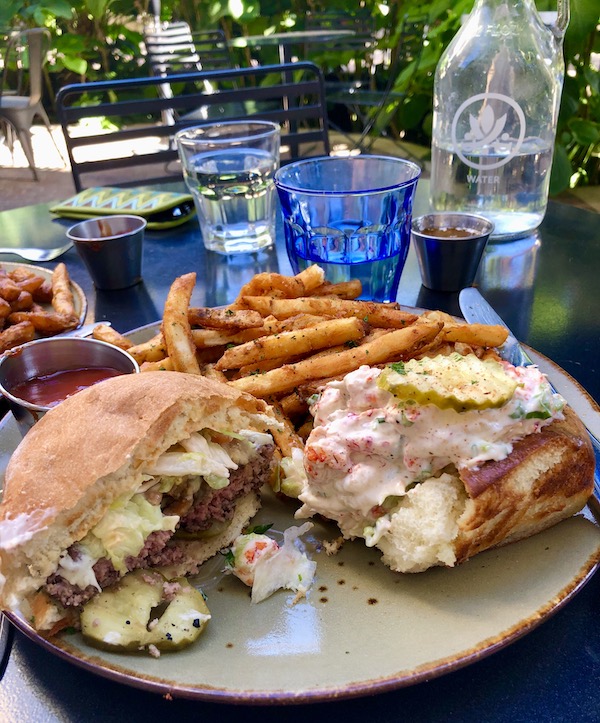 A white plate topped with a half of a cheeseburger, half a lobster roll and french fries eat en route Coast to Coast We Did It!