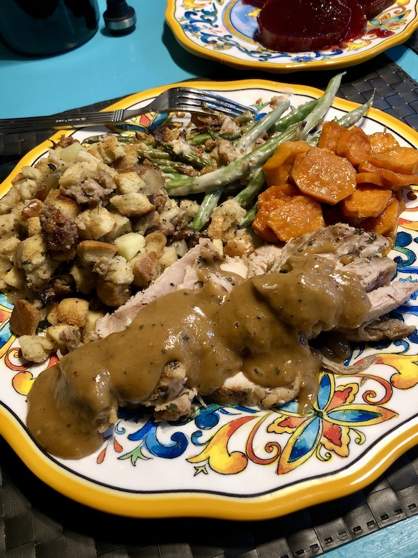 A colorful plate topped with turkey, gravy, stuffing, green beans and sweet potato slices eaten en route Coast to Coast We Did It!