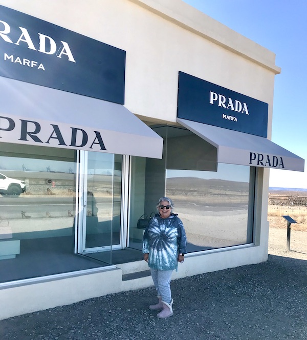 A white building storefront with a woman in front en route Coast to Coast We Did It!