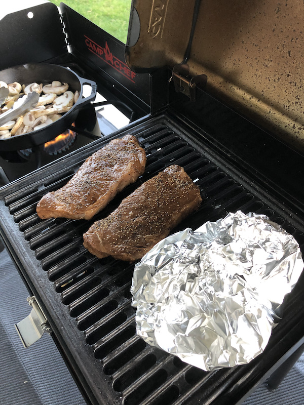 Steak and mushrooms in a cast iron pan on the grill on our trip Coast to Coast We Did It!