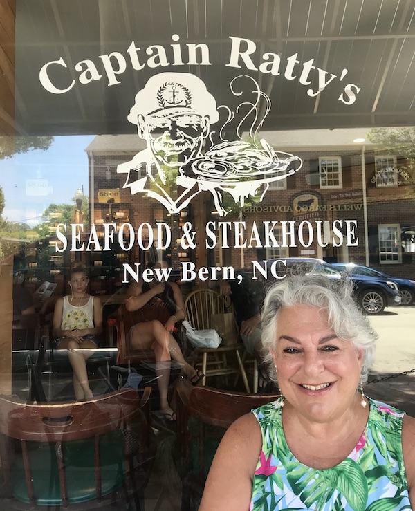 A woman with silver hair sitting in front of a restaurant window on our route Coast to Coast We Did It!