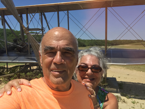 A man and woman in front of an old biplane en route Coast to Coast We Did It!