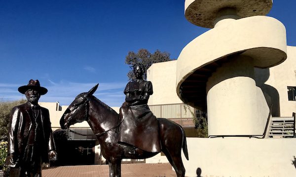 A bronze sculpture of a man standing and a woman on a horse in front of a white spiral staircase in #rvlife #rvtravel #fulltimerv #lifeontheroad #rving #rvliving