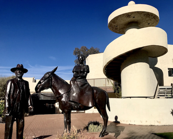 A bronze sculpture of a man standing and a woman on a horse in front of a white spiral staircase in #rvlife #rvtravel #fulltimerv #lifeontheroad #rving #rvliving