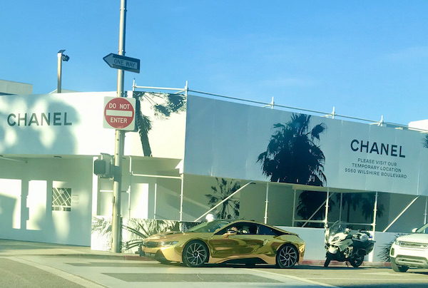 A large white store with a solid gold sports car in front in Opulent Beverly Hills California