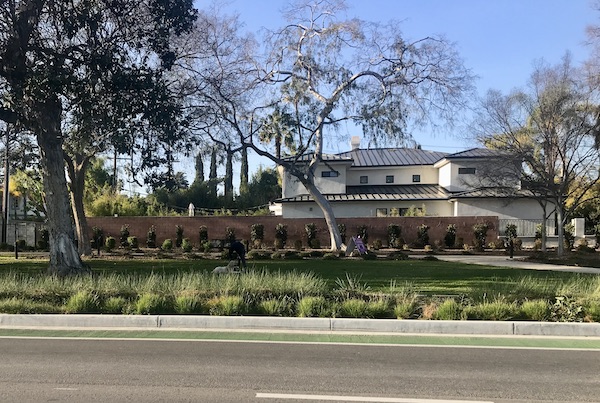 A huge white house with lush landscaping in Opulent Beverly Hills California