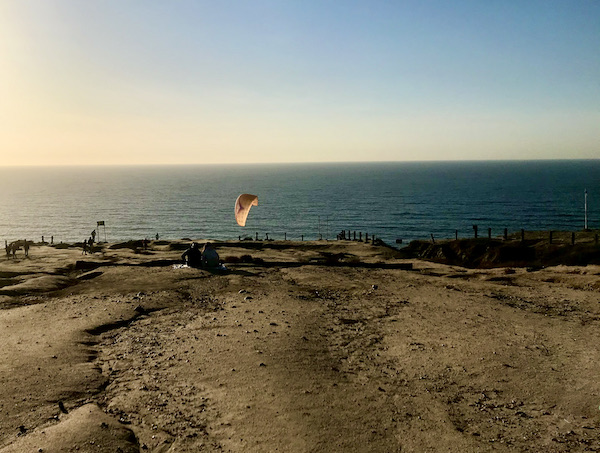Beach and ocean with someone hang gliding in San Diego California