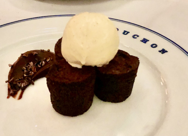 A cream colored plate topped with a trio of round brownies, vanilla ice cream and a smear of chocolate at Thomas Keller's Bouchon Las Vegas