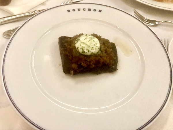 A cream colored plate topped with a flat iron steak and a pat of seasoned butter at Thomas Keller's Bouchon Las Vegas