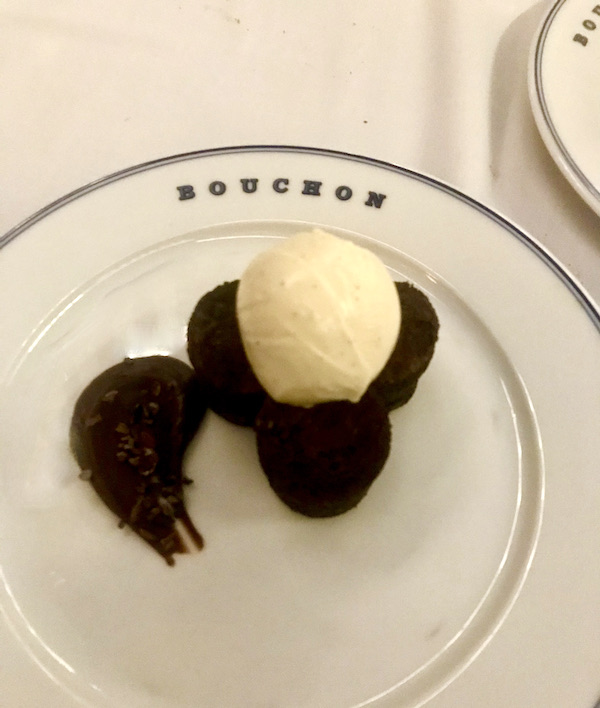 A cream colored plate topped with a trio of round brownies, vanilla ice cream and a smear of chocolate at Thomas Keller's Bouchon Las Vegas
