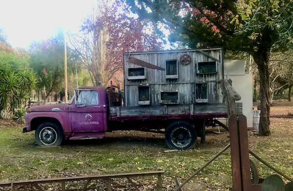 An old red pickup truck with a wooden chicken coop in the truck bed at Casa de Fruta Hollister California