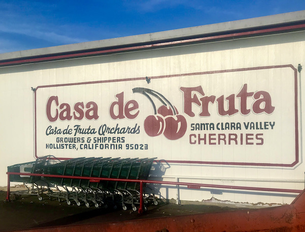 A huge sign on the side of a building with red letters Casa de Fruta and black shopping carts in front at Casa de Fruta Hollister California