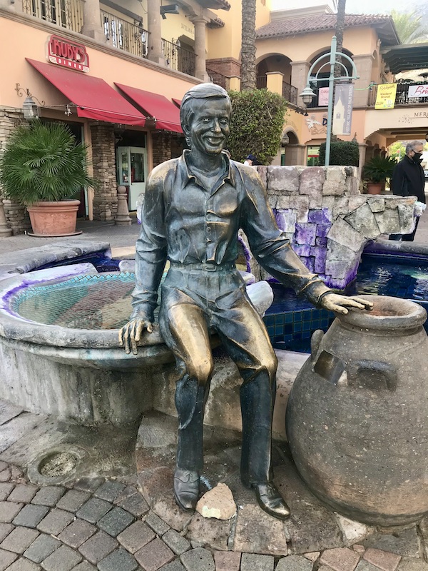 A bronze sculpture of of man sitting on the edge of a fountain near Great Shakes in Palm Springs California