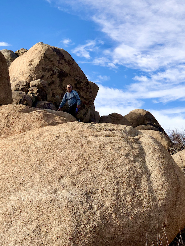A man climbing a huge rock at Joshua Tree National Park