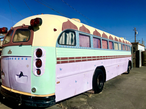 An old bus painted pale yellow, mint and lavender near Joshua Tree National Park