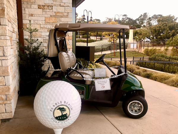 A green golf cart against a stone wall with a very large golf ball telling you that you're at Pebble Beach on the Scenic 17-mile Drive Monterey California