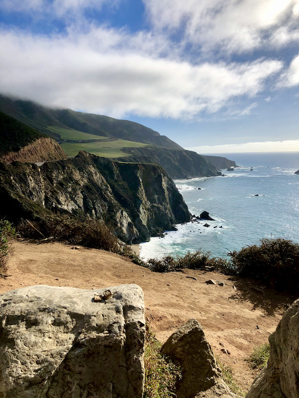 Mountain cliffs with lush green grass, dirt, rocks and ocean below near the Scenic 17-mile Drive Monterey California