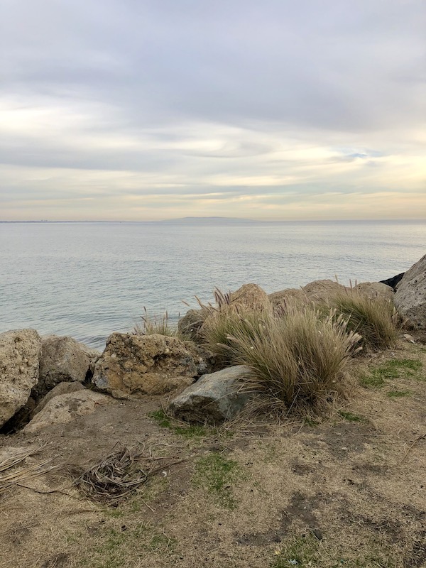 Rocky cliff, sand, ocean and cloudy sky along the Southern California Coast