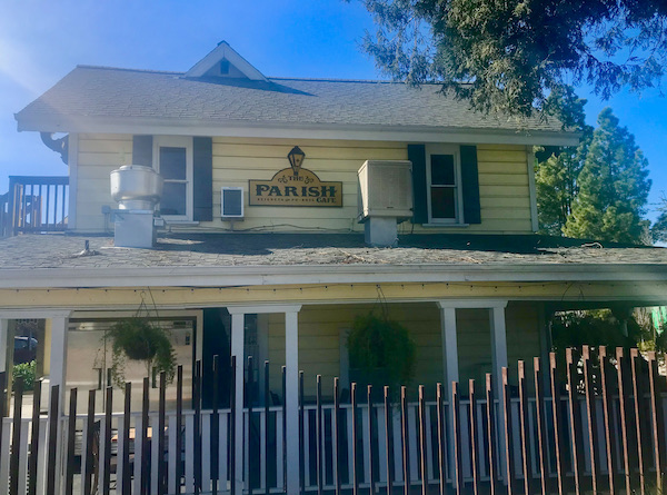 A yellow building with white pillars and picket fence housing The Parish Café offering A Taste of New Orleans in Healdsburg CA