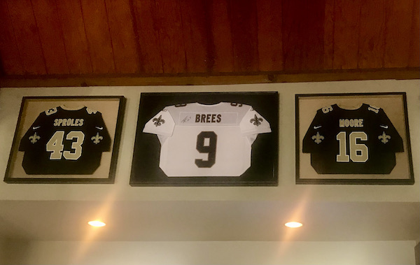 Three football jerseys in clear cases hanging on the wall at A Taste of New Orleans in Healdsburg CA