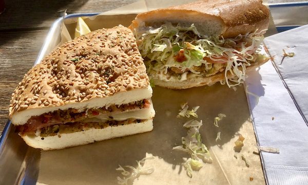 A wedge of an Italian sandwich and half of an oyster Po' boy on brown paper lined sheet tray offered us A Taste of New Orleans in Healdsburg CA