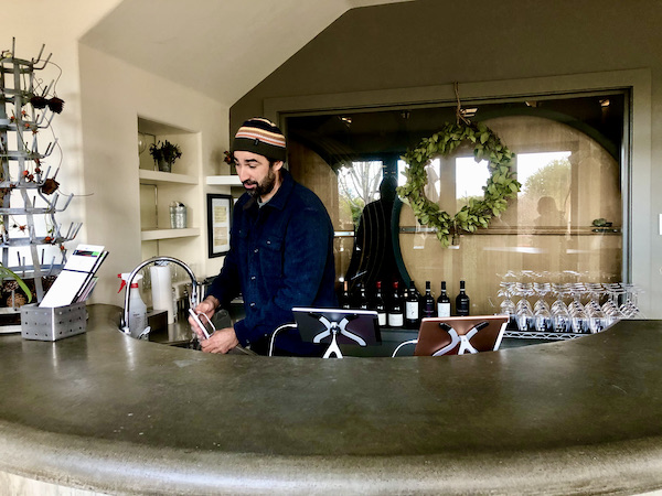 A man behind a wine bar cleaning a metal siphon, part of our Behind the Scenes at Stuhlmuller Vineyards