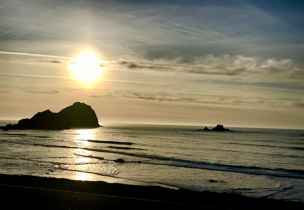 The sun setting over an ocean with rocks. Very moody near Jedediah Smith Redwoods Crescent City CA