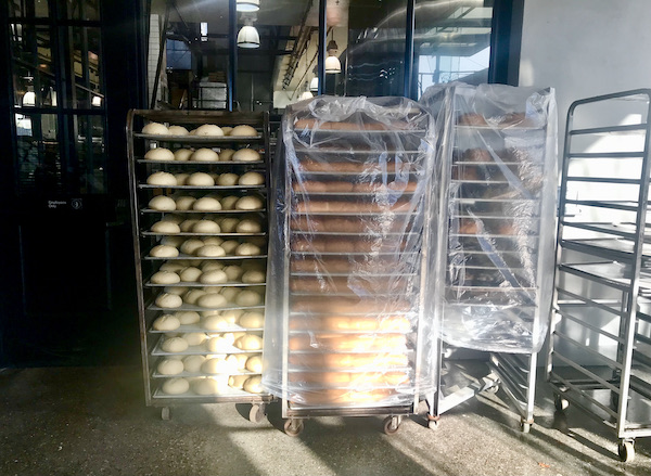 Metal speed racks filled with bread that are covered in plastic in San Francisco California