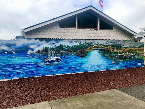A mural of an ocean sean with mountains and clouds near The Hungry Clam Brookings Oregon