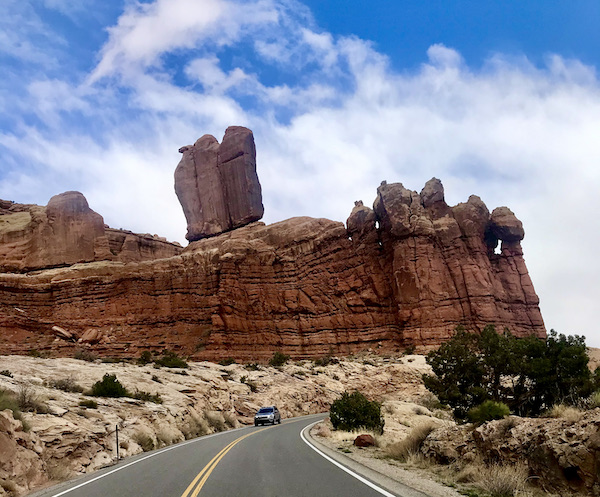 A mountain with rocks that look like they could tumble down on the road below at Arches National Park Moab Utah