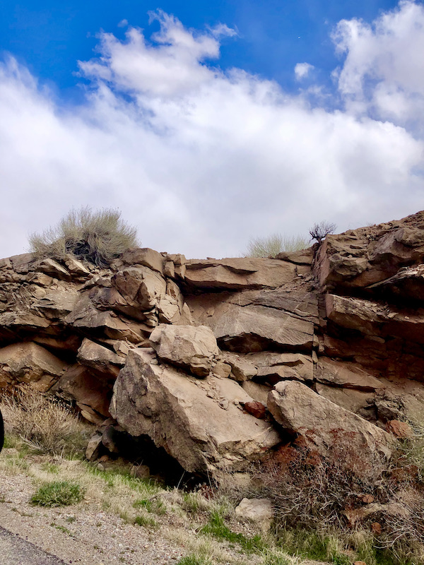 Rocks tumbled down on a mountainside with white clouds above at Arches National Park Moab Utah
