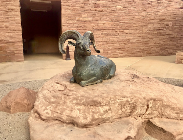 A bronze sculpture of a ram lying on a rock at Arches National Park Moab Utah