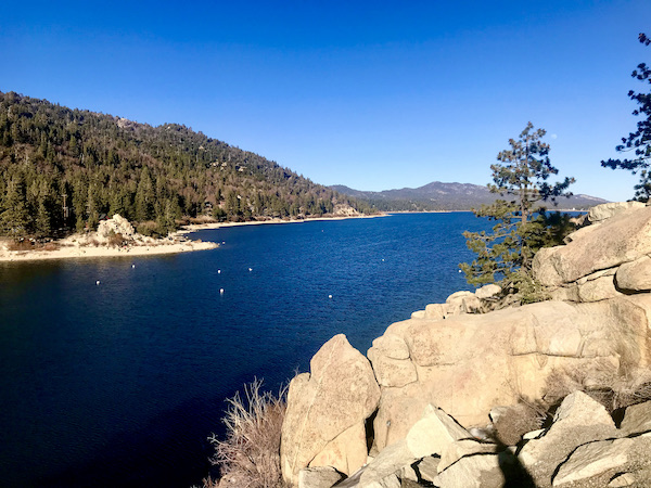 A very deep blue lake surrounded by rocks and tree covered mountains at Big Bear Lake California