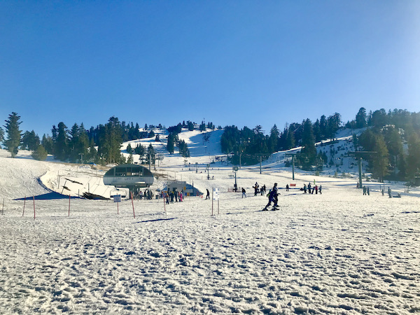 A snow covered slope with skiers and trees at Big Bear Lake California