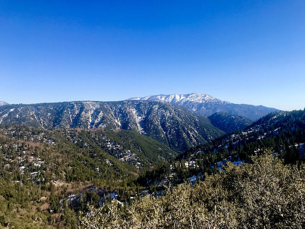 Trees, green mountains and snow dusted mountains in distance at Big Bear Lake California