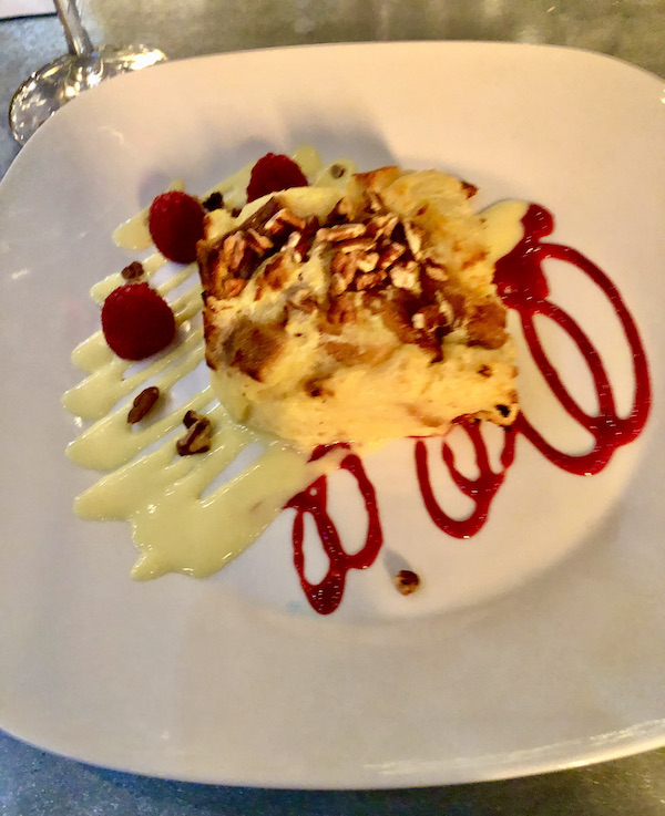 A white plate topped with a creamy yellow dessert with pecans and raspberries at Coyote Sonoma in Healdsburg CA