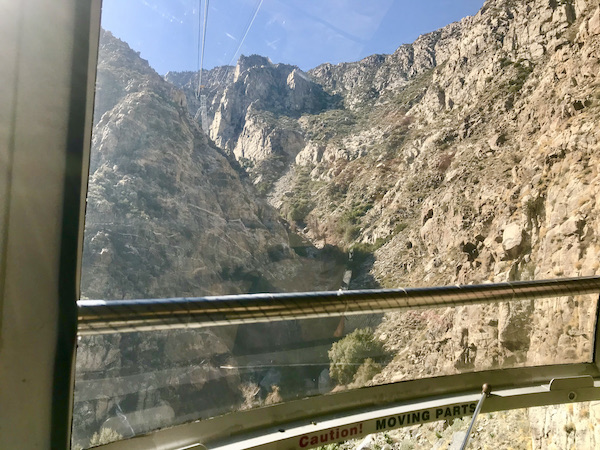 Looking out at mountains from inside a huge glass window on the Palm Springs Aerial Tramway California
