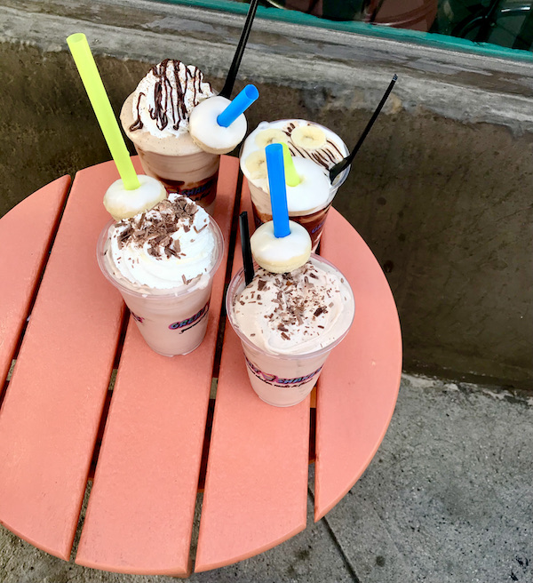 Four milkshakes with straws and doughnuts on a coral painted round table after our trip up the Palm Springs Aerial Tramway California