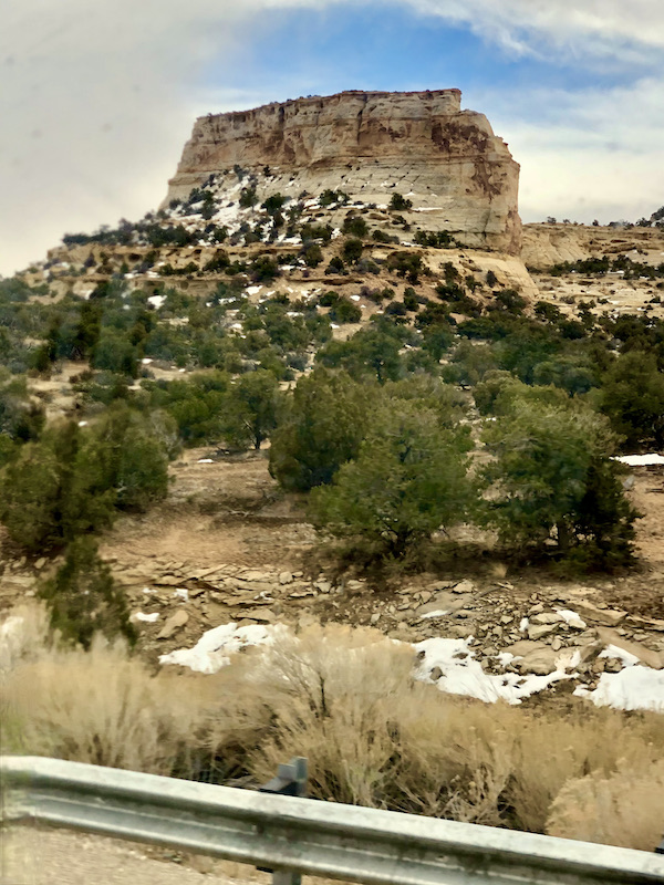 Patches of snow on the ground with trees and mountains on our Scenic Drive to Moab Utah