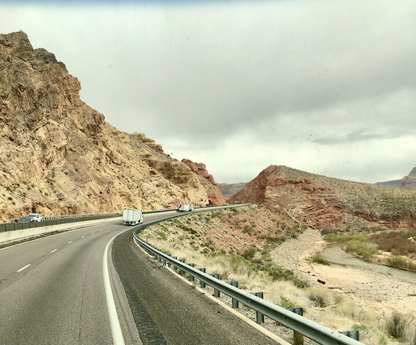 Scenic Drive to Moab Utah highway with reddish colored mountains and grey sky.