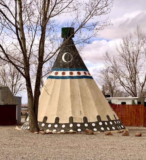 Black and white tipi on sand next to a tree on our Scenic Drive to Moab Utah