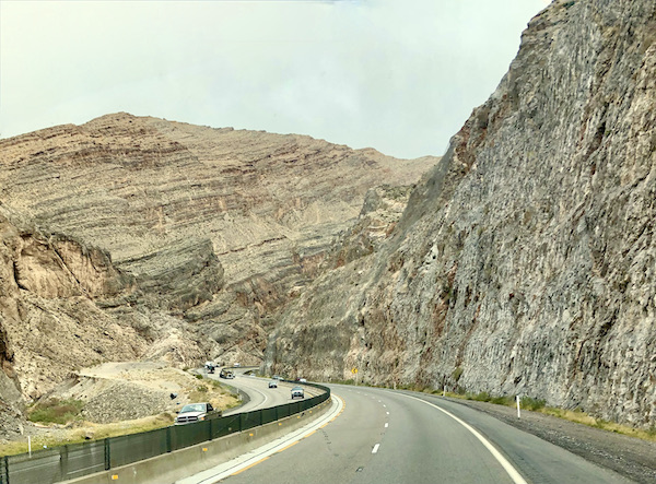 Highway planked by beige mountains along our Scenic Drive to Moab Utah