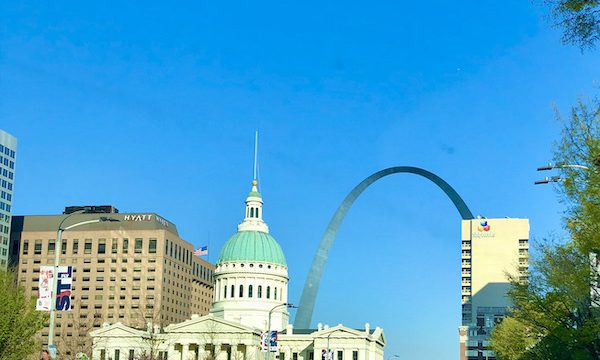 Looking down a paved street with a view of the old courthouse and the gateway arch in Downtown St. Louis Missouri