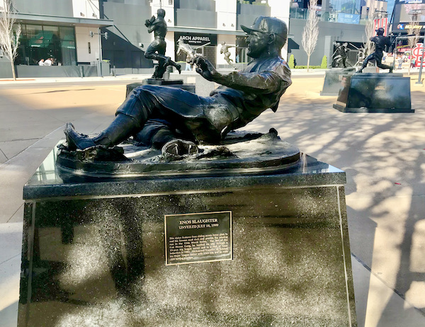 A bronze sculpture of a baseball player sliding on the ground.